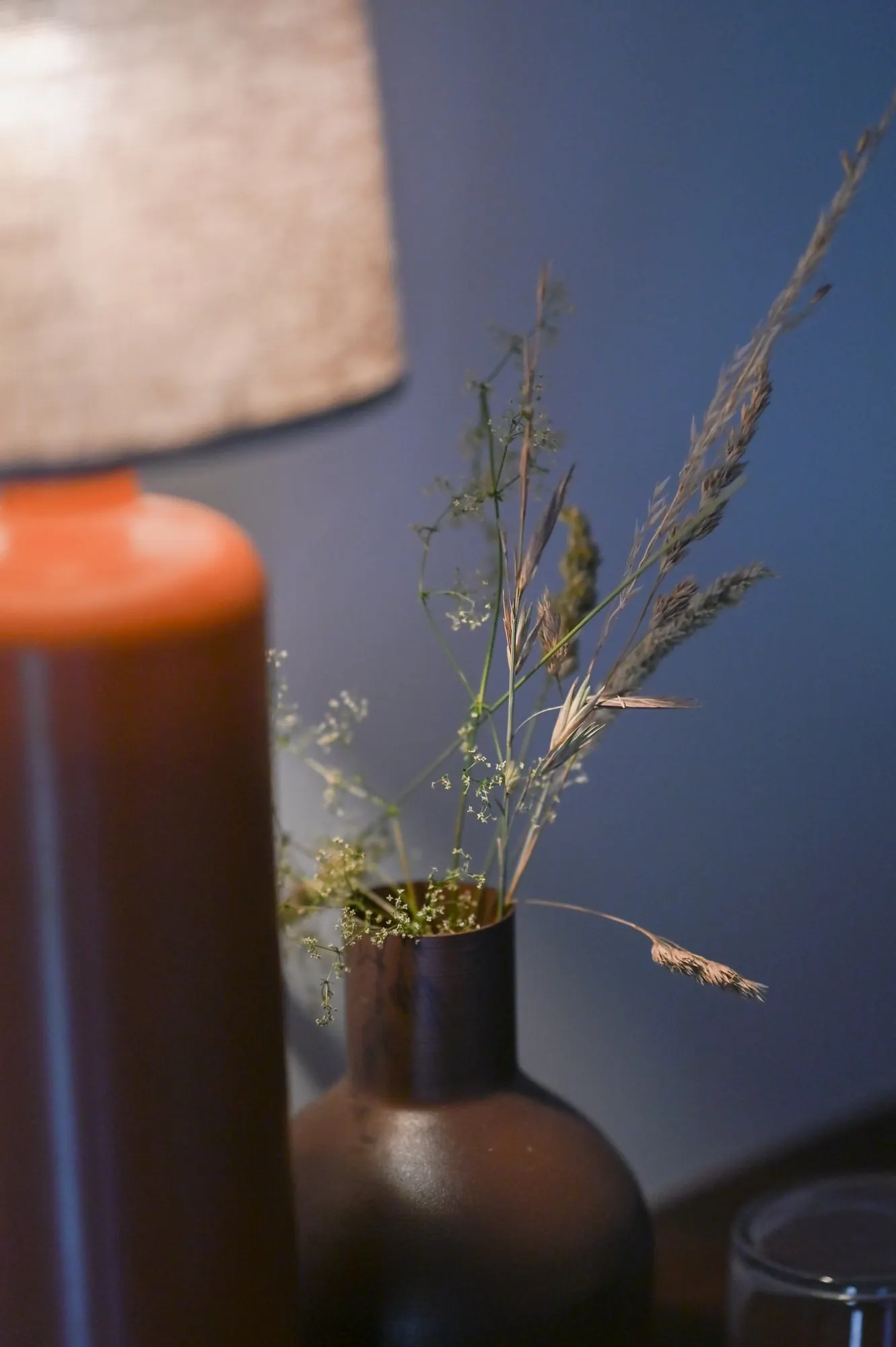 A terracotta lamp and dried grasses in evening light