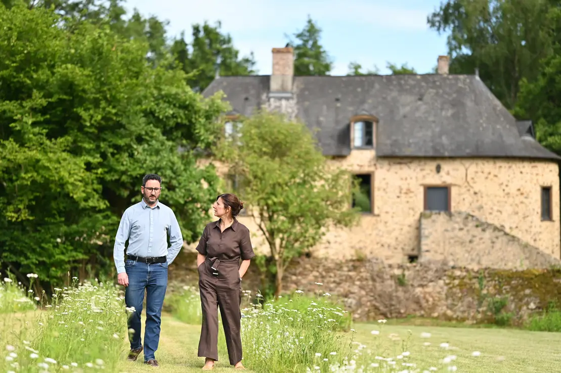 Deux personnes marchant dans une prairie fleurie devant le domaine