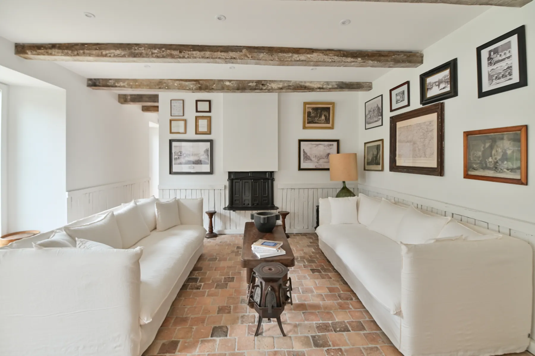 A sitting room with white sofas and exposed beams