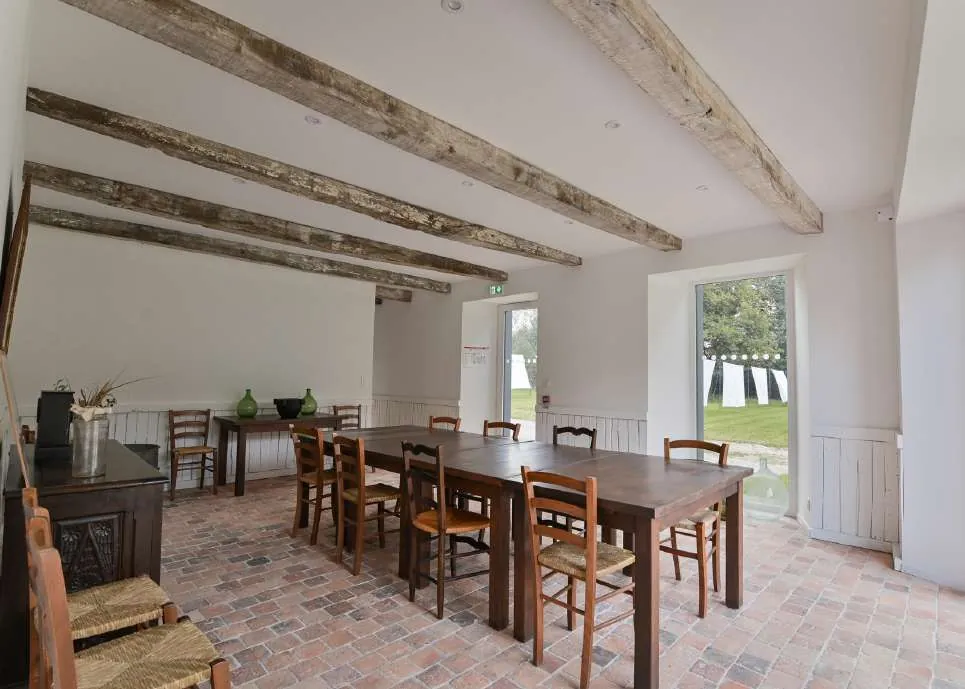 A bright room with old beams and a long wooden table where a group can gather to make